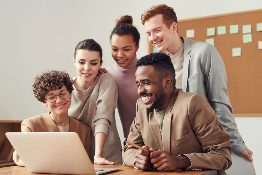 A mentor guiding a small group through a project on a laptop